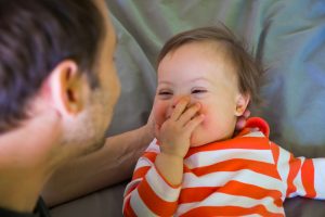 Down syndroma baby playing with dad